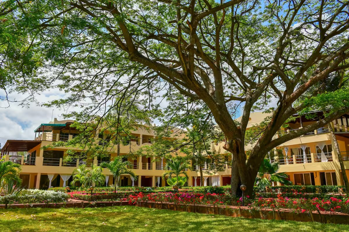Le Pleiadi's mature shade tree, tropical gardens and cream apartment buildings