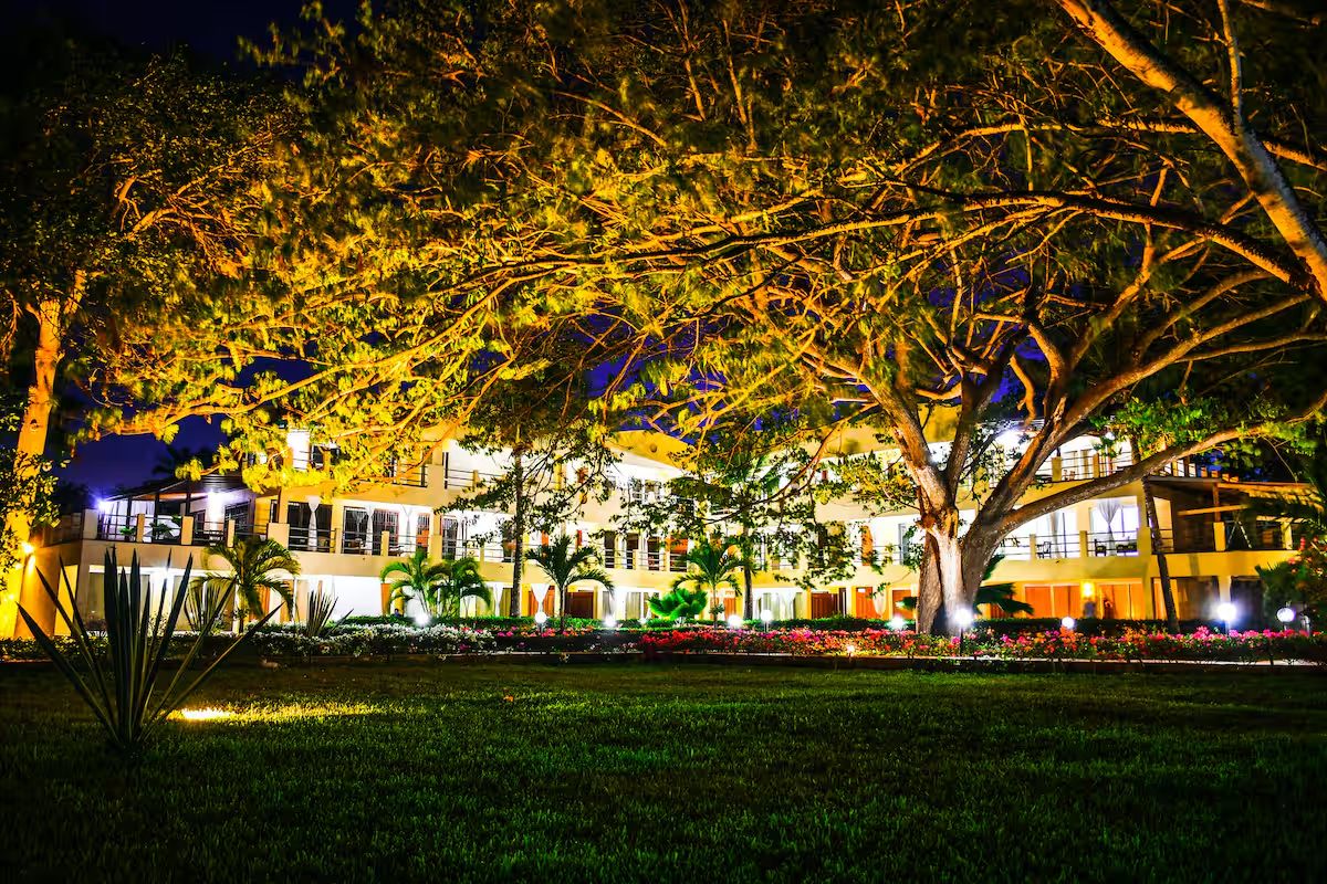 Le Pleiadi's mature trees and warmly lit apartments after dusk